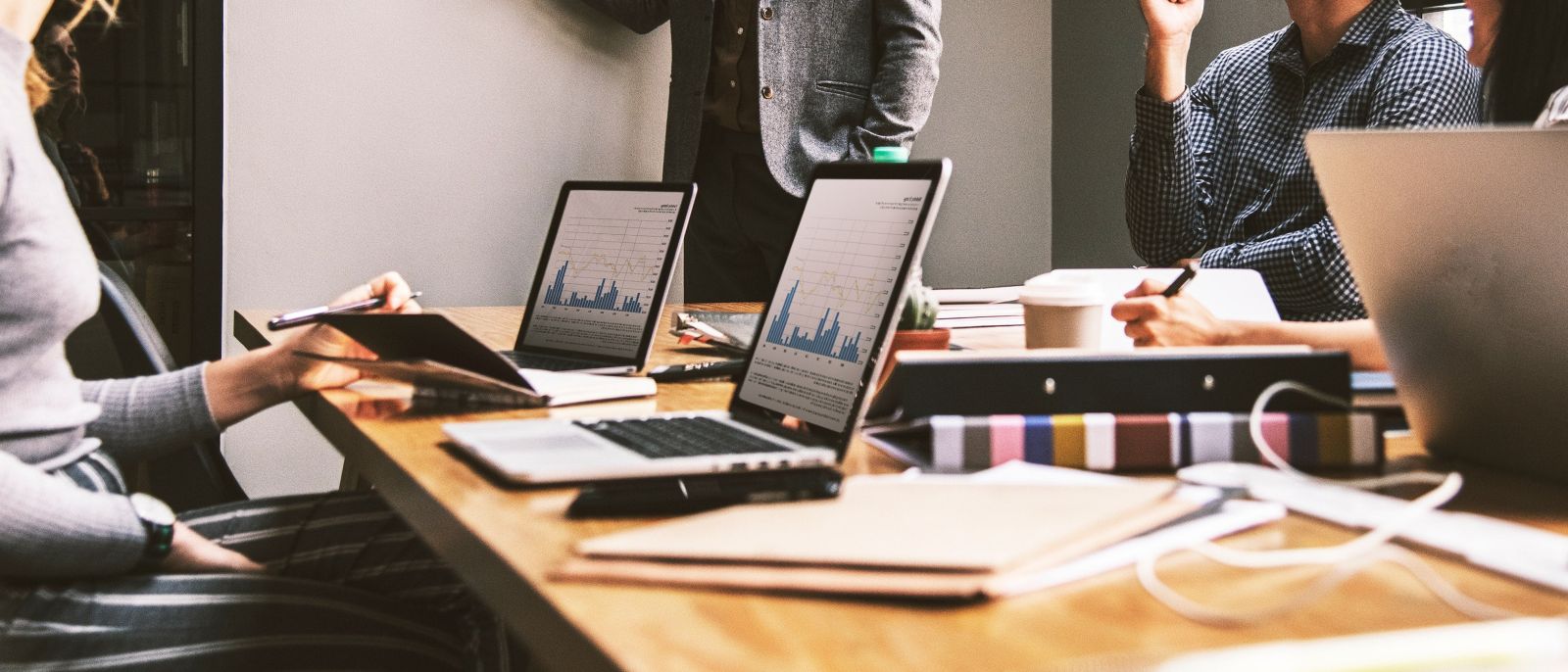 Equipa em sessão de trabalho com portáteis e gráficos