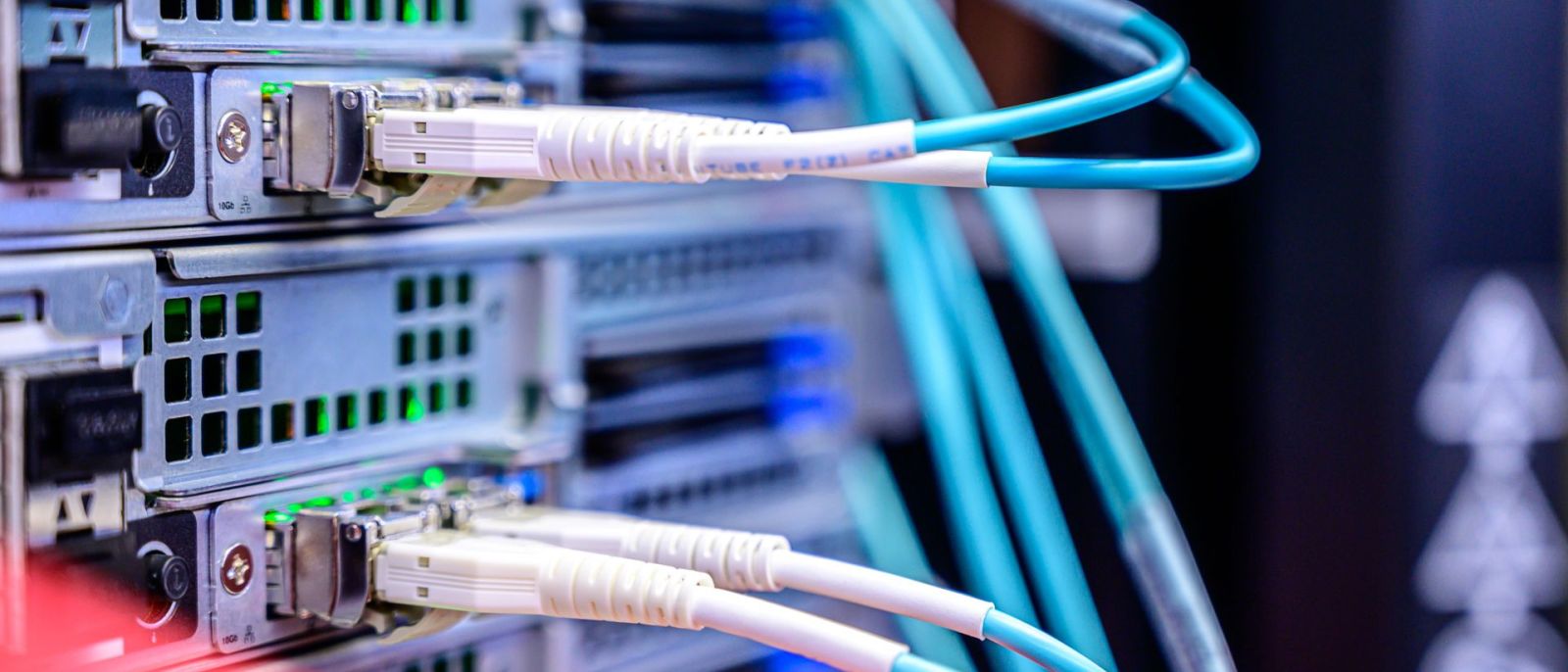 Cabos de fibra ótica ligados a equipamento de rede num bastidor